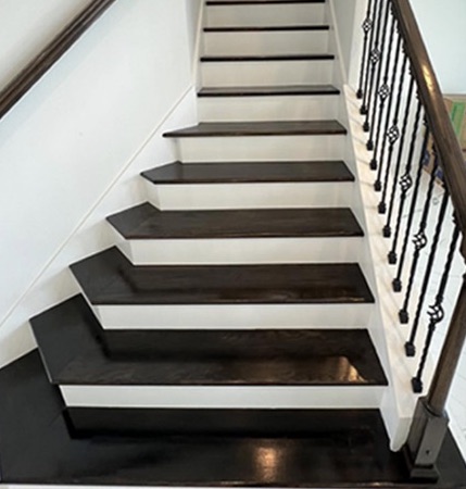 Staircase with dark-stained wood treads, white risers and iron balusters