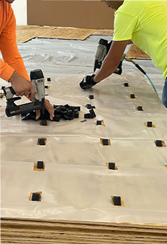 Installer nailing down hardwood planks over paper underlayment