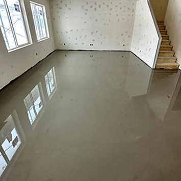 Smooth, freshly poured self-leveling floor in an open unfinished room with stairs